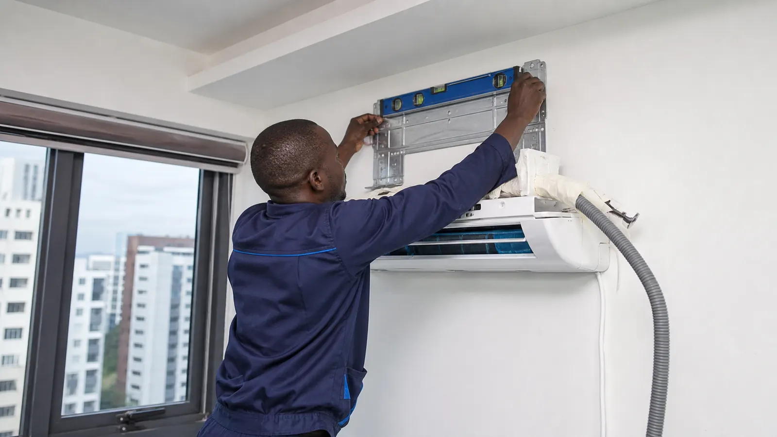 Technician installing a wall mounted split AC in a Nairobi apartment or office